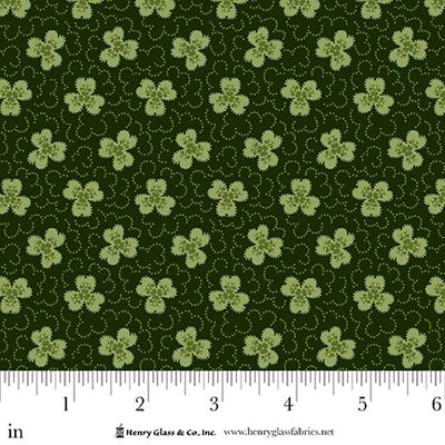 Green fabric with small clover patterns and a ruler at the bottom for scale.