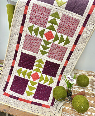 Runner with purple, green and pink pieced pattern on a wooden surface