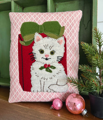 Decorative pillow with a cat or kitten design, and a red present with a bow