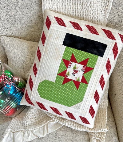 Decorative pillow with pieced Christmas stocking design and striped border.